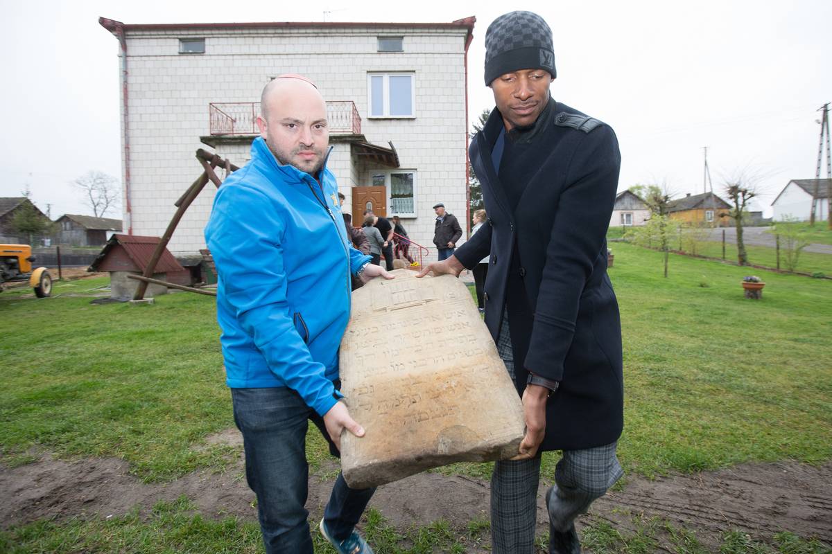 Allen and Daniels carrying a Jewish headstone that would be returned to a nearby Jewish cemetery. (Image by Elan Kawesch)
