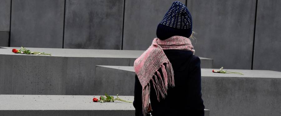 A woman look at flowers placed on the concrete columns of the Holocaust memorial during the international Holocaust Remembrance Day in Berlin on January 27, 2016. 
