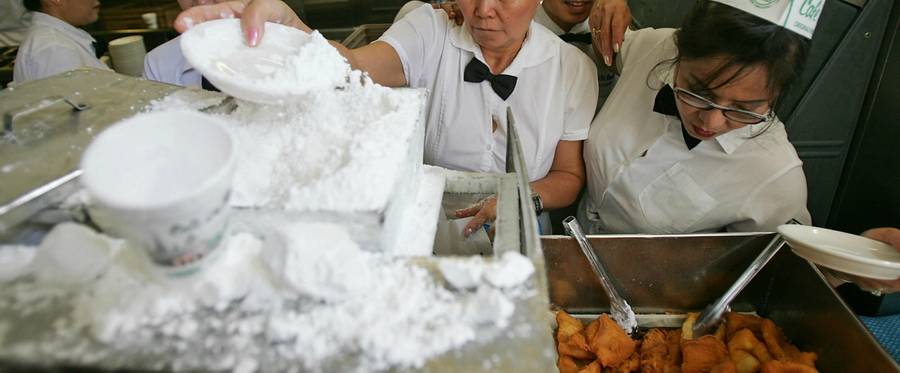 Waitresses prepare beignets covered with powdered sugar at Café du Monde, August 9, 2006. 