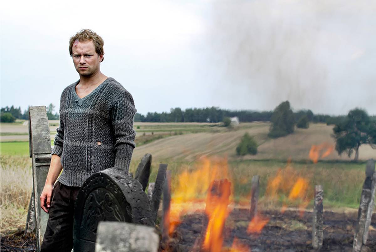 Józek (Maciej Stuhr) watches his cemetery of exhumed Jewish gravestones go up in flames. (Menemsha Films)