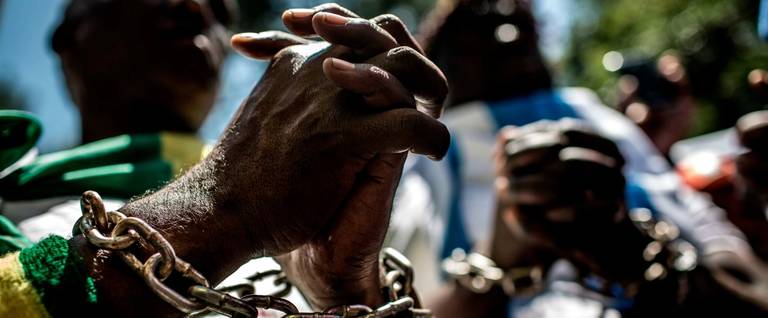 Members of the Africa Diaspora Forum (ADF), civil society organisations, churches, trade unions and other coalitions wear chains and shout slogans during a demonstration against the slave trade and human trafficking in Libya on December 12, 2017 at the Union Buildings in Pretoria.