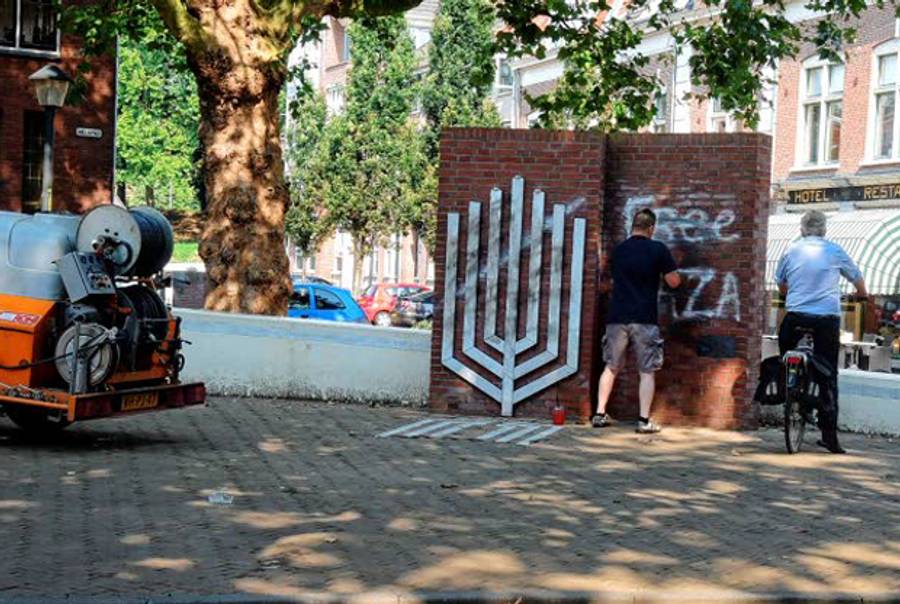 Man removes 'Free Gaza' graffiti from Holocaust memorial in Gorinchem, Netherlands. (gp-foto)