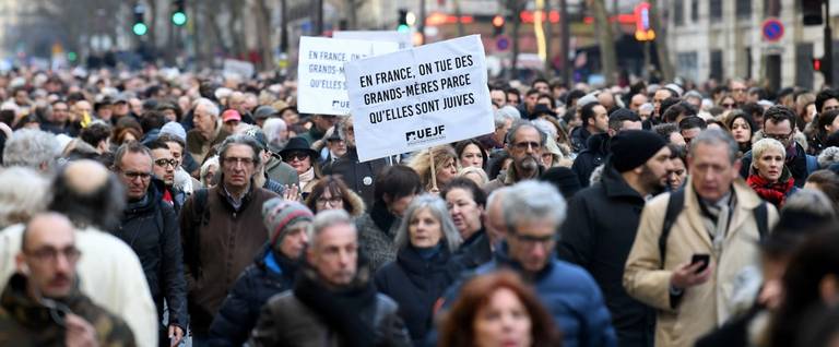 Participants walk holding placards during a slient march in Paris on March 28, 2018, in memory of Mireille Knoll, an 85-year-old Jewish woman murdered in her home in what police believe was an anti-Semitic attack.