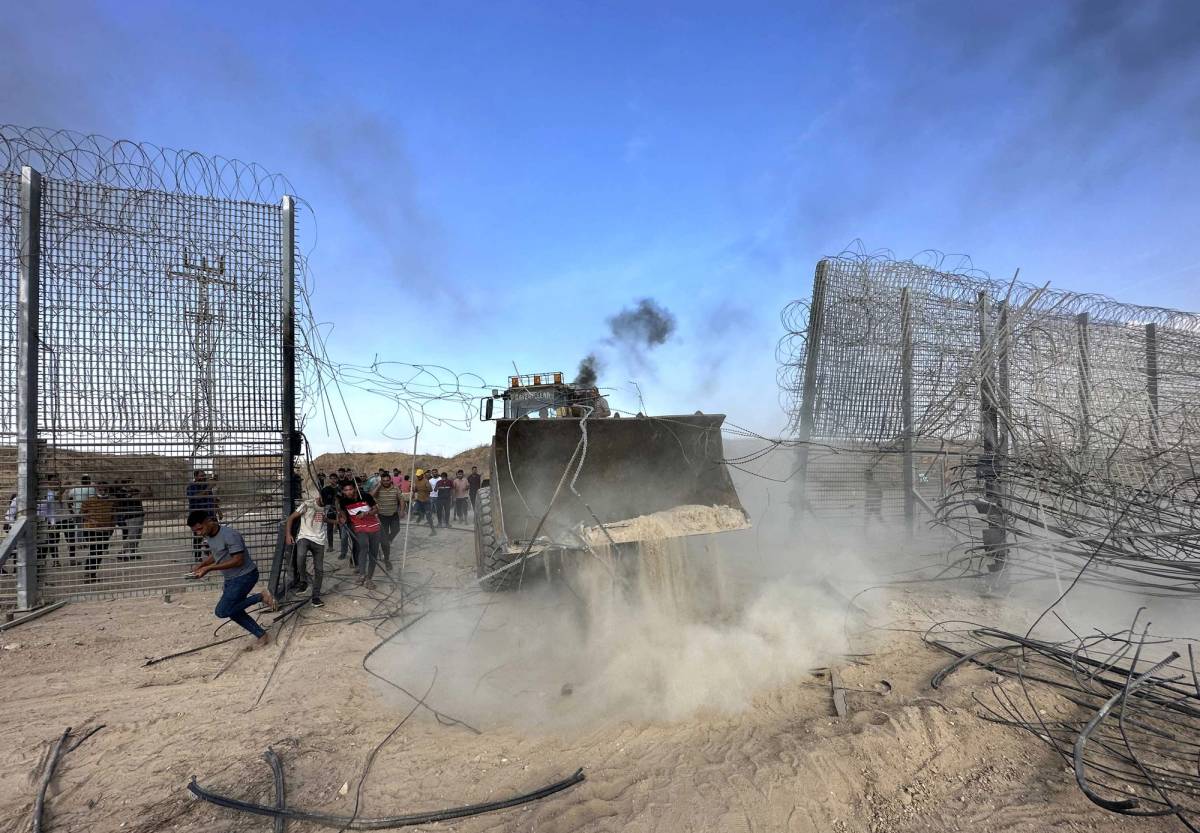 Palestinian groups break through a fence with the help of a digger on Oct. 7, 2023
