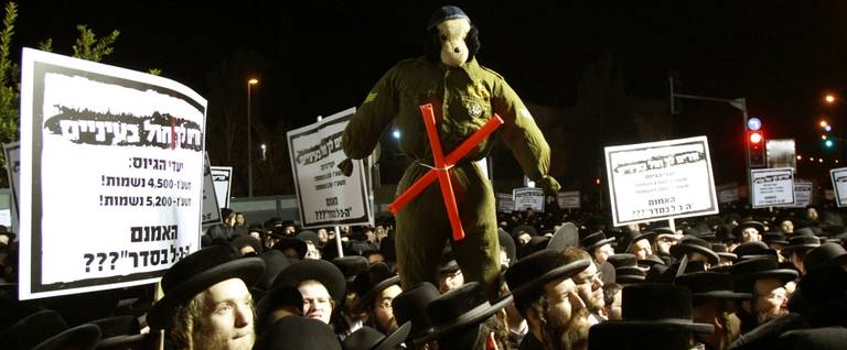Ultra-Orthodox Jewish men hold placards against military service during a protest against any plans to end the exemption of the ultra-Orthodox young men studying at seminaries from military service, Jerusalem, December 22, 2015.  