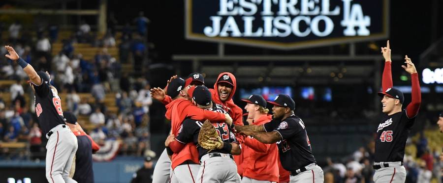 Patrick Corbin and Howie Kendrick of the Washington Nationals celebrate with teammates after the final out of the tenth inning as the Nationals defeated the Los Angeles Dodgers 7-3 in game five to win the National League Division Series at Dodger Stadium on October 09, 2019 in Los Angeles, California.