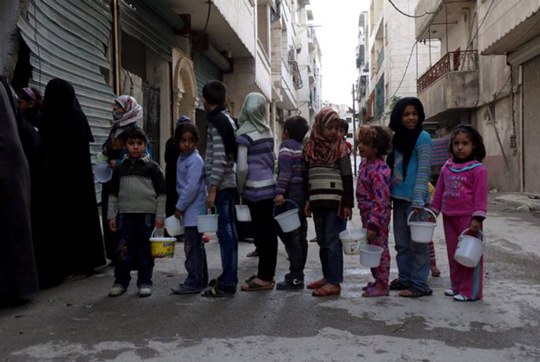 Syrian children line up to receive food aid from a community kitchen in the Myassar district of Aleppo on November 23, 2014. (IZEIN AL-RIFAI/AFP/Getty Images)