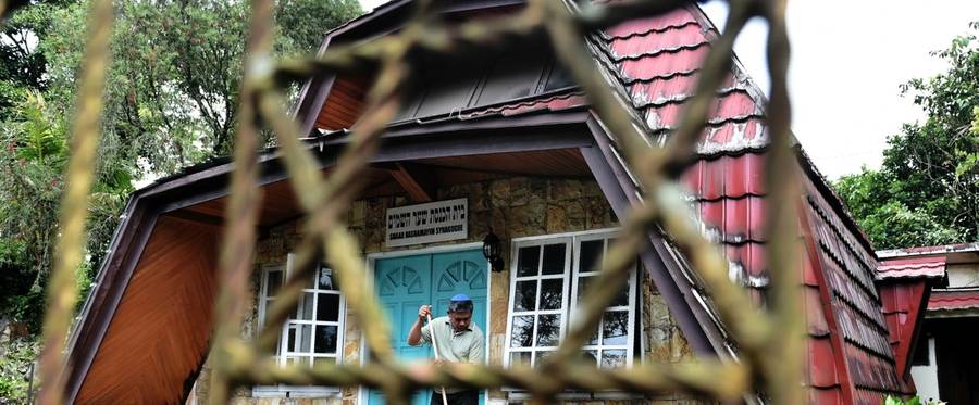 This photograph taken on February 17, 2017 shows a member of Indonesia's Jewish community sweeping the steps to the synagogue ahead of a prayer service in Tondano, North Sulawesi.
