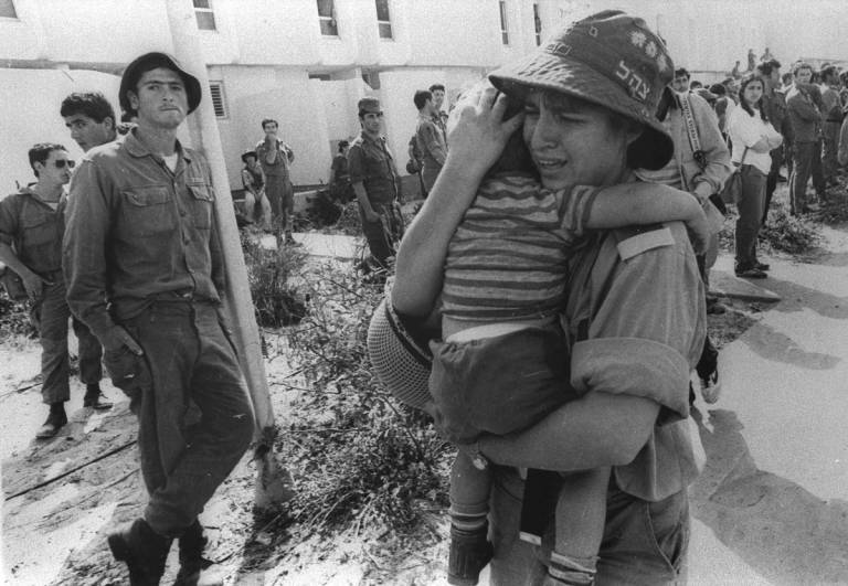 An Israeli woman soldier cries as she evacuates a Jewish settler child from an apartment building in the Sinai Desert settlement of Yamit, as part of Israel's peace treaty with Egypt, 1982