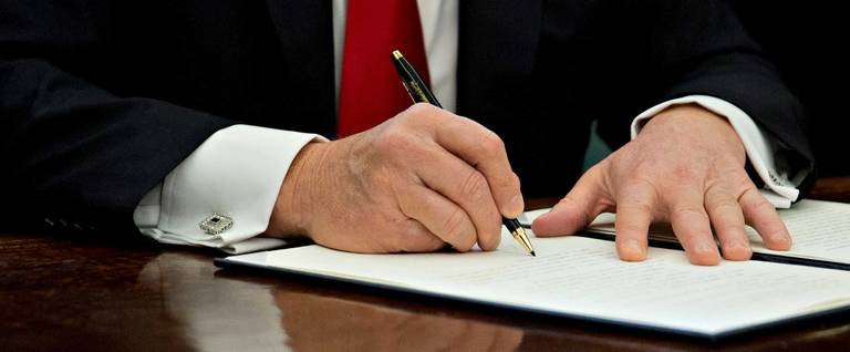 U.S. President Donald Trump signs an executive order in the Oval Office of the White House January 30, 2017 in Washington, DC.
