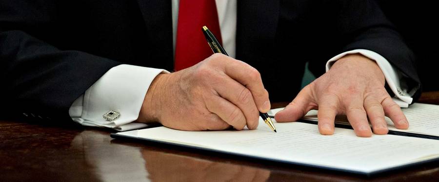 U.S. President Donald Trump signs an executive order in the Oval Office of the White House January 30, 2017 in Washington, DC.
