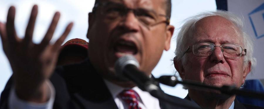 U.S. Rep. Keith Ellison speaks as Sen. Bernie Sanders looks on during a rally on jobs December 7, 2016 at Freedom Plaza in Washington, DC.
