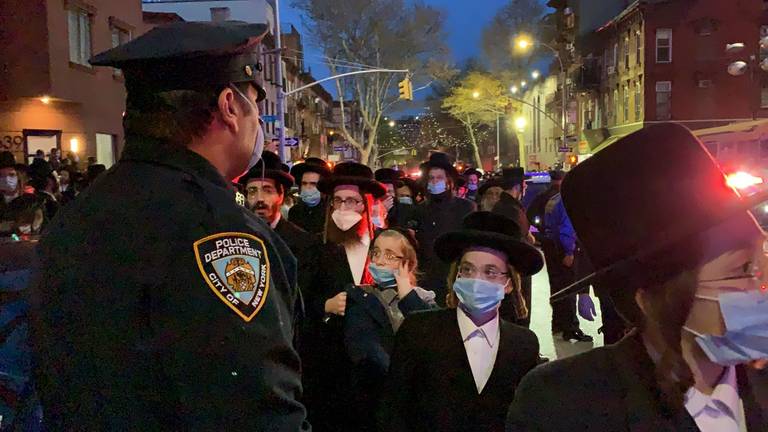 A New York City police officer keeps watch as hundreds of mourners gather in Brooklyn for the funeral of Rabbi Chaim Mertz, a Hasidic Orthodox leader whose death was reportedly tied to the coronavirus, on April 28, 2020