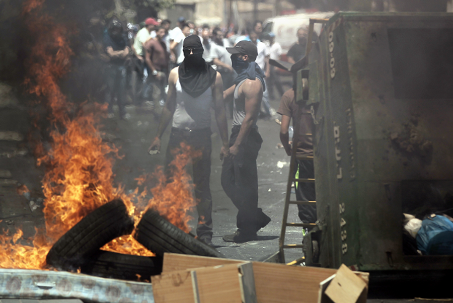 Palestinians stand behind burning tires during clashes with Israeli security forces following traditional Friday prayers near the Old City in East Jerusalem on July 25, 2014. (Getty Images)