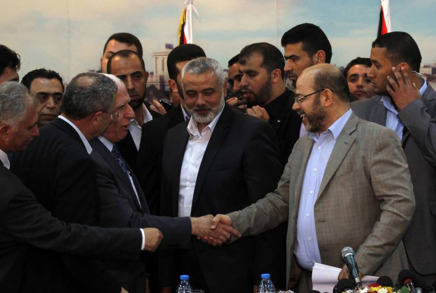 Fatah delegation chief Azzam al-Ahmed (C-L) shakes hands with Hamas deputy leader Musa Abu Marzuk (R) in the presence of Hamas prime minister in the Gaza Strip Ismail Haniya (C), after the signing of a reconciliation agreement in Gaza on April 23, 2014. (Said Khatib/AFP/Getty Images)