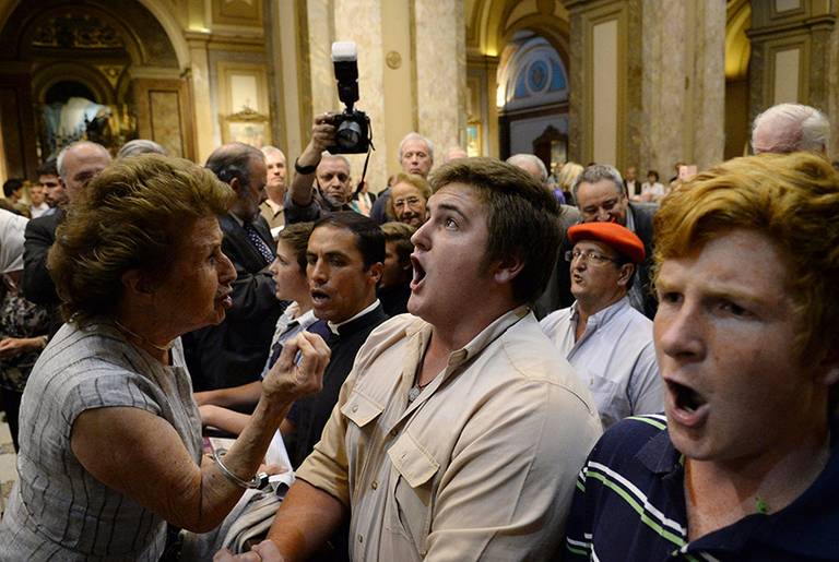 A woman attending a ceremony that marks the beginning of the Holocaust, left, tries to stop ultra-traditionalist Catholics from interrupting an interfaith event at the Metropolitan Cathedral in Buenos Aires, Argentina, on Nov. 12, 2013.(Rodolfo Pezzoni/AP)