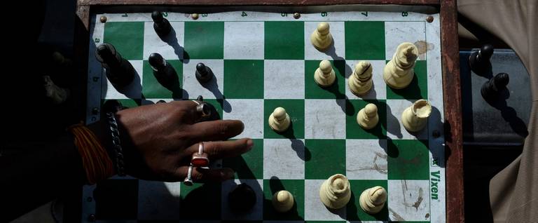 Indian commuters play chess as they sit on the roadside in Kolkata, November 20, 2013