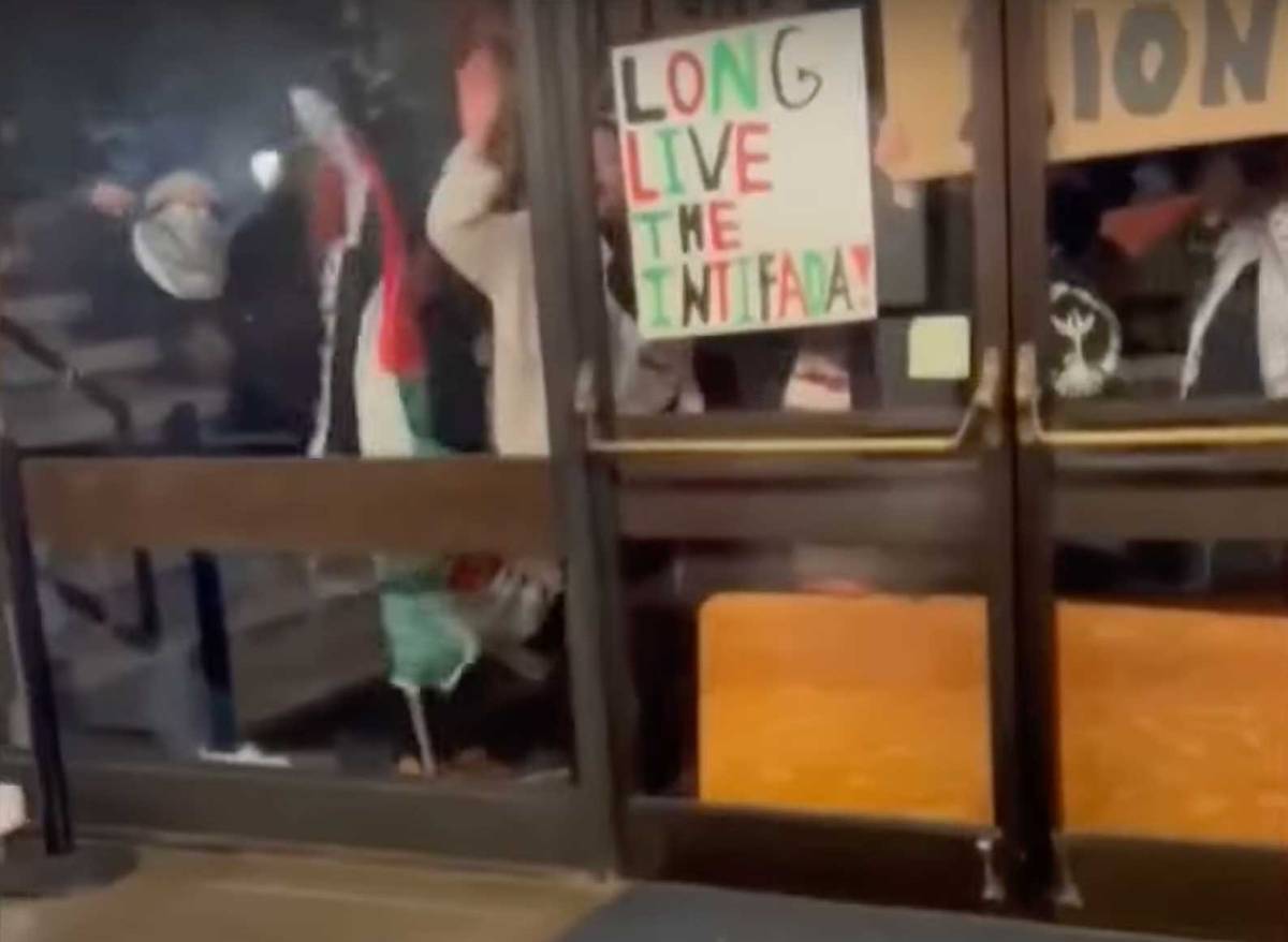 Protesters bang on windows (shortly before the glass was smashed) to disrupt the Ran Bar-Yoshafat event last month