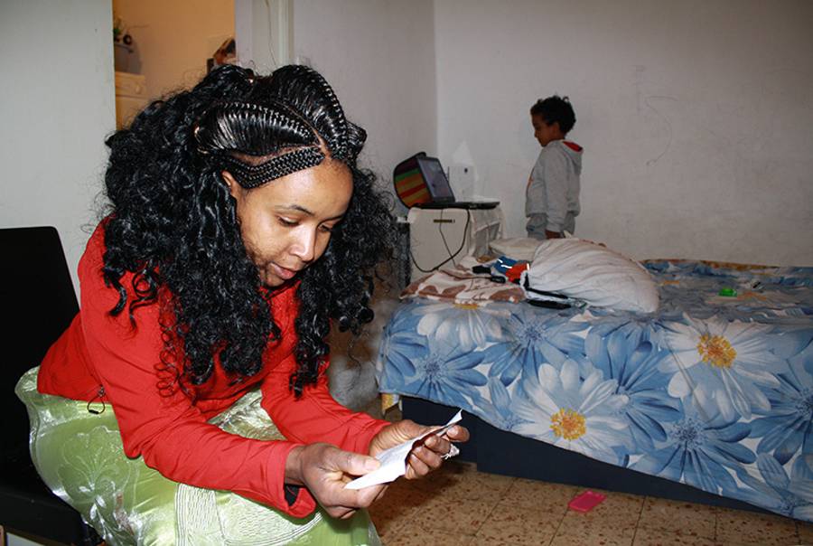 Rahwa Hayle holds her conditional release permit; in the background, her son Nachum watches videos. (Asher Greenberg)