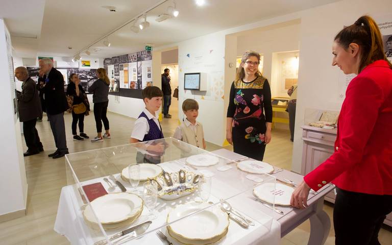Young museum visitors view an exhibit featuring an everyday table setting from the 19th century, displayed alongside Therese Berger's 19th-century Haggadah at Budapest’s Hungarian Museum of Trade and Tourism