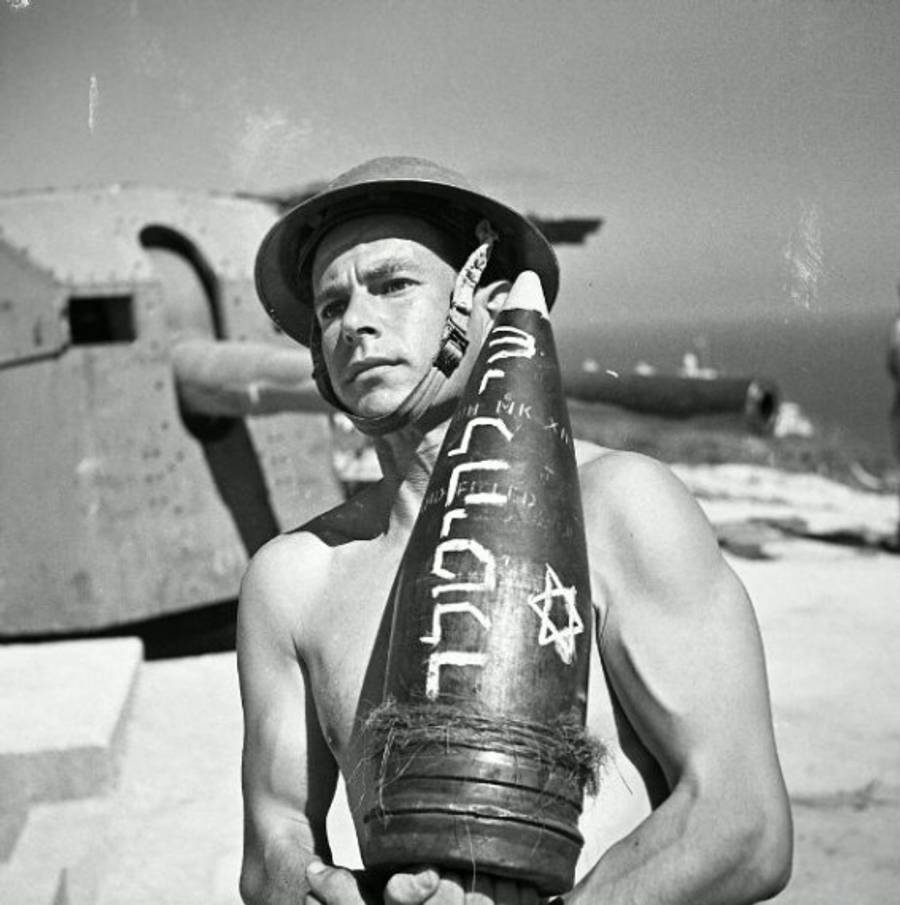 Joseph Wald, a Jewish Brigade soldier, carries an artillery shell. The Hebrew inscription on the shell translates to ‘A gift to Hitler.’