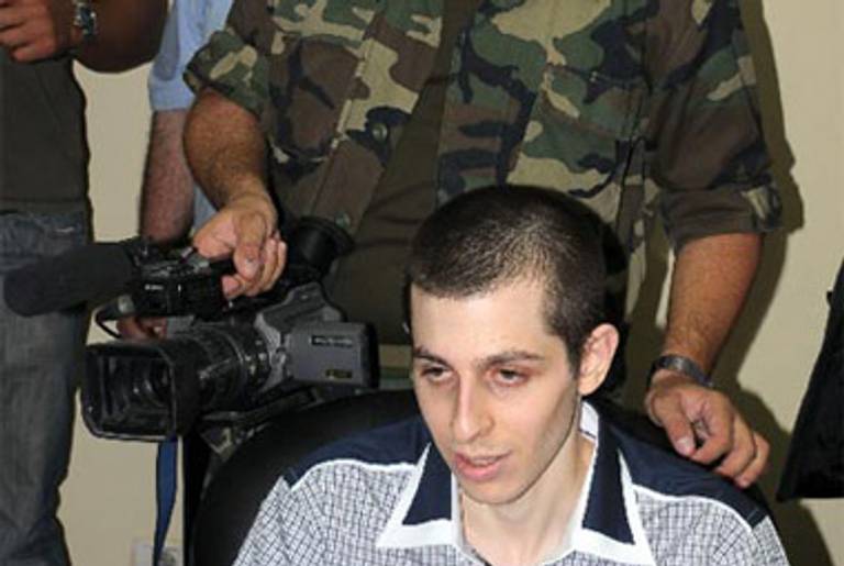 Shalit during his forced television interview. The hand on his shoulder belongs to a masked Hamas man.(AP/Ynet)
