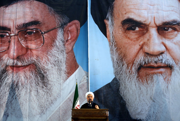 Iranian President Hassan Rouhani delivers a speech under portraits of Iran's supreme leader Ayatollah Ali Khamenei (L) and Iran's founder of the Islamic Republic, Ayatollah Ruhollah Khomeini (R), on June 3, 2014. (ATTA KENARE/AFP/Getty Images)