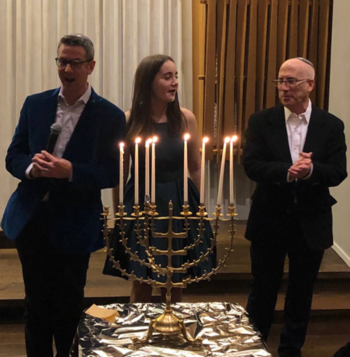 Shirley and her parents light the menorah at her bat mitzvah (Photo: Allison Diamond)