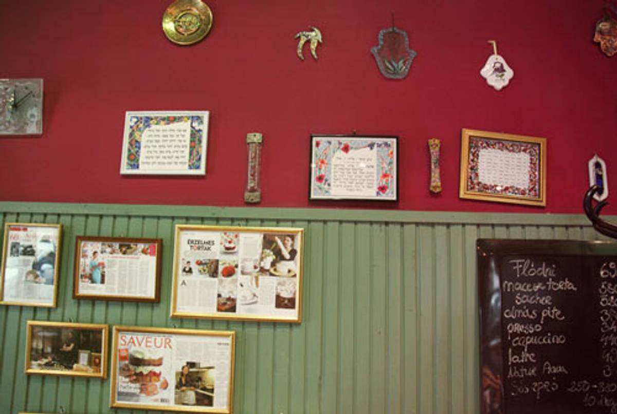 The walls of Rachel Raj’s Tortaszalon coffeeshop are decorated with Judaica, along with printed copies of features in leading newspapers and magazines. (Photo: Daniella Cheslow)