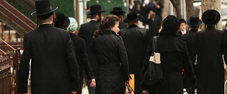 Hasidic men and women walk through a Jewish Orthodox neighborhood in Brooklyn on April 24, 2017.