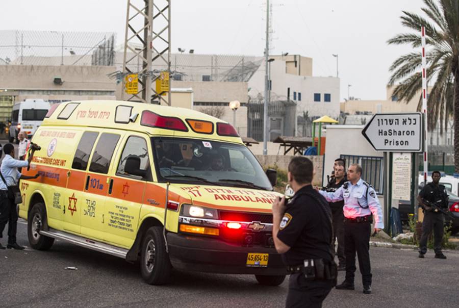 Israeli guards escort an ambulance out of HaSharon high security prison, 40 kilometers northeast of Tel Aviv, on February 23, 2014, after an American-Israeli prisoner serving life for murder was shot dead after he seized a gun and opened fire on three guards. (JACK GUEZ/AFP/Getty Images)