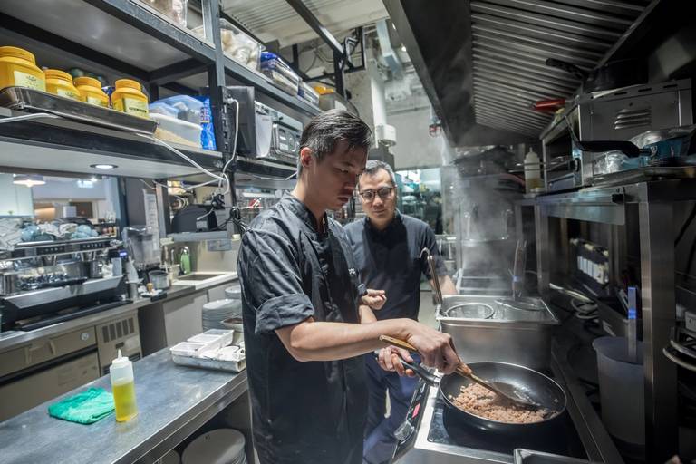 A chef cooks spaghetti Bolognese made with plant-based omnipork at Hong Kong’s Kind Kitchen restaurant, on June 20, 2019. Looking on is David Yeung, co-founder and co-chief executive officer of Green Monday.