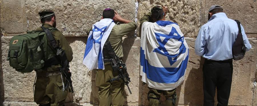 Israeli soldiers pray with their national flags at the Western Wall on June 5, 2016 in Jerusalem's old city, as they celebrate Jerusalem Day, that marks the anniversary of the 'reunification' of the holy city after Israel captured the Arab eastern sector from Jordan during the 1967 Six-Day War. 