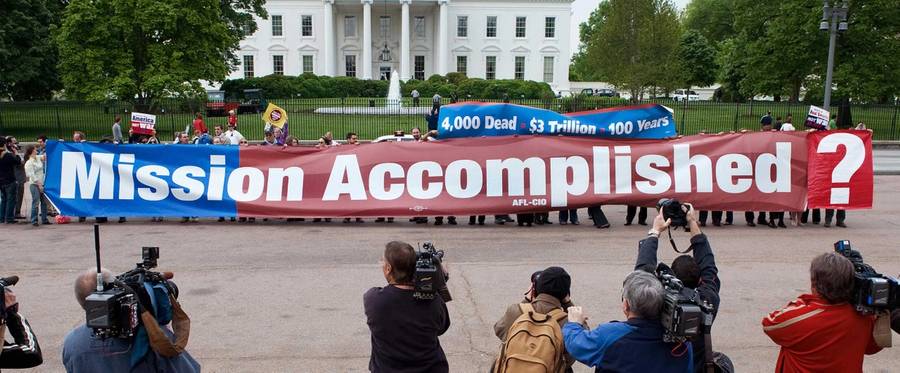 Members of the 'The Iraq Campaign 2008' hold a large replica of 'Mission Accomplished' banner on Pennsylvania Avenue in front of the White House in Washington, DC May 1, 2008, marking the fifth anniversary of President Bush's 'Mission Accomplished' speech after landing on board a US aircraft carrier, proclaiming the end of major combat operations in Iraq.