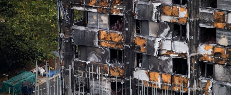 Scaffolding is seen with coverings at the base of the burned-out-shell of Grenfell Tower in London on October 17, 2017.
