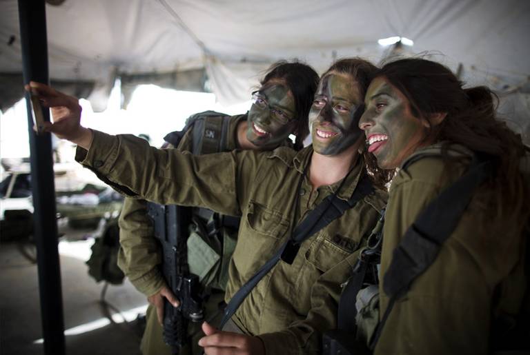 ﻿Israeli female soldiers of the Karakal Battalion with their faces painted in camouflage photograph themselves before a graduation march in the northern part of the Negev desert, on March 13, 2013.(Menahem Kahana/AFP/Getty Images)