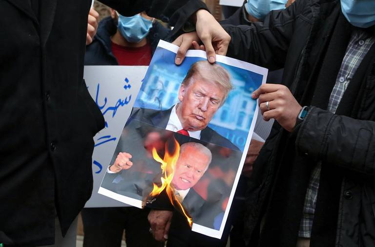 Students of Iran’s Basij paramilitary force burn posters depicting U.S. President Donald Trump (top) and President-elect Joe Biden, during a rally in front of the Foreign Ministry in Tehran on Nov. 28, 2020, to protest the killing of prominent nuclear scientist Mohsen Fakhrizadeh a day earlier