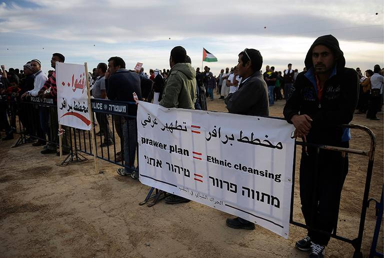 Bedouin demonstrators stand next to placards erected during a protest against the Prawer Plan in the southern village of Hura on Nov. 30, 2013. The so-called Prawer-Begin Bill calls for the relocation of 30,000 to 40,000 Bedouin, the demolition of about 40 villages, and the confiscation of more than 700,000 dunums (70,000 hectares) of land in the Negev.(David Buimovitch/AFP/Getty Images)