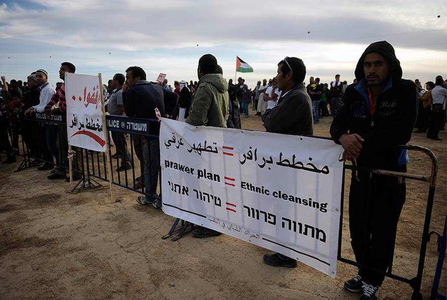 Bedouin demonstrators stand next to placards erected during a protest against the Prawer Plan in the southern village of Hura on Nov. 30, 2013. The so-called Prawer-Begin Bill calls for the relocation of 30,000 to 40,000 Bedouin, the demolition of about 40 villages, and the confiscation of more than 700,000 dunums (70,000 hectares) of land in the Negev.(David Buimovitch/AFP/Getty Images)