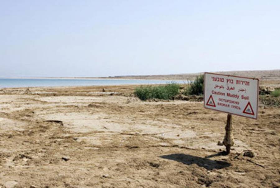 A sign warning of muddy soil is seen near Ein Gedi on the retreating shores of the Dead Sea on September 10, 2008.(JONATHAN NACKSTRAND/AFP/Getty Images.)